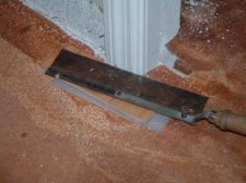 Cutting a door jamb with hand saw to install laminate flooring