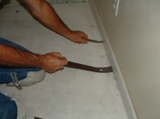 I'm using two pry bars to pry the baseboard up from the bottom so I will not damage the drywall on the wall.