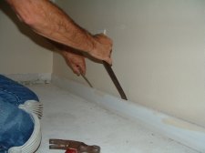 Use the pry bars to pry the baseboard away from the wall so you will not push in the drywall