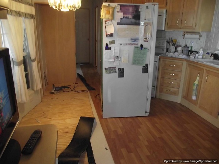 Moving the refrigerator onto the installed laminate flooring in the kitchen.