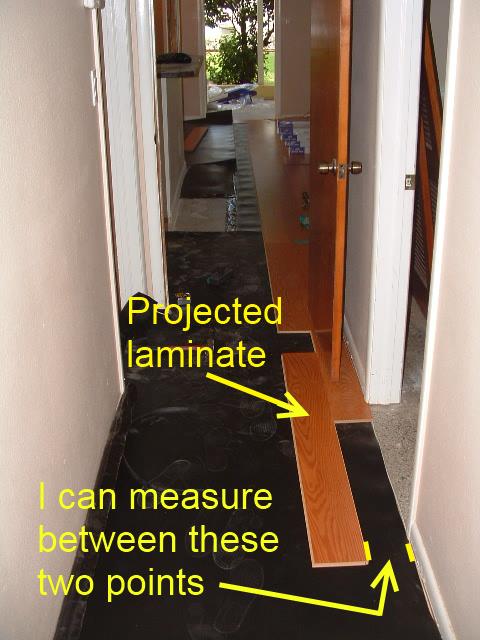 Installing laminate in hallway, taking measurement.