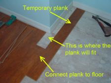 Cutting laminate around corners is easier when I install this temporary plank.