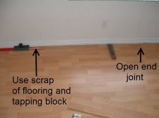 Installing the last row of laminate flooring, Here I will use a tapping block and a scrap piece of laminate to connect the end joint together.